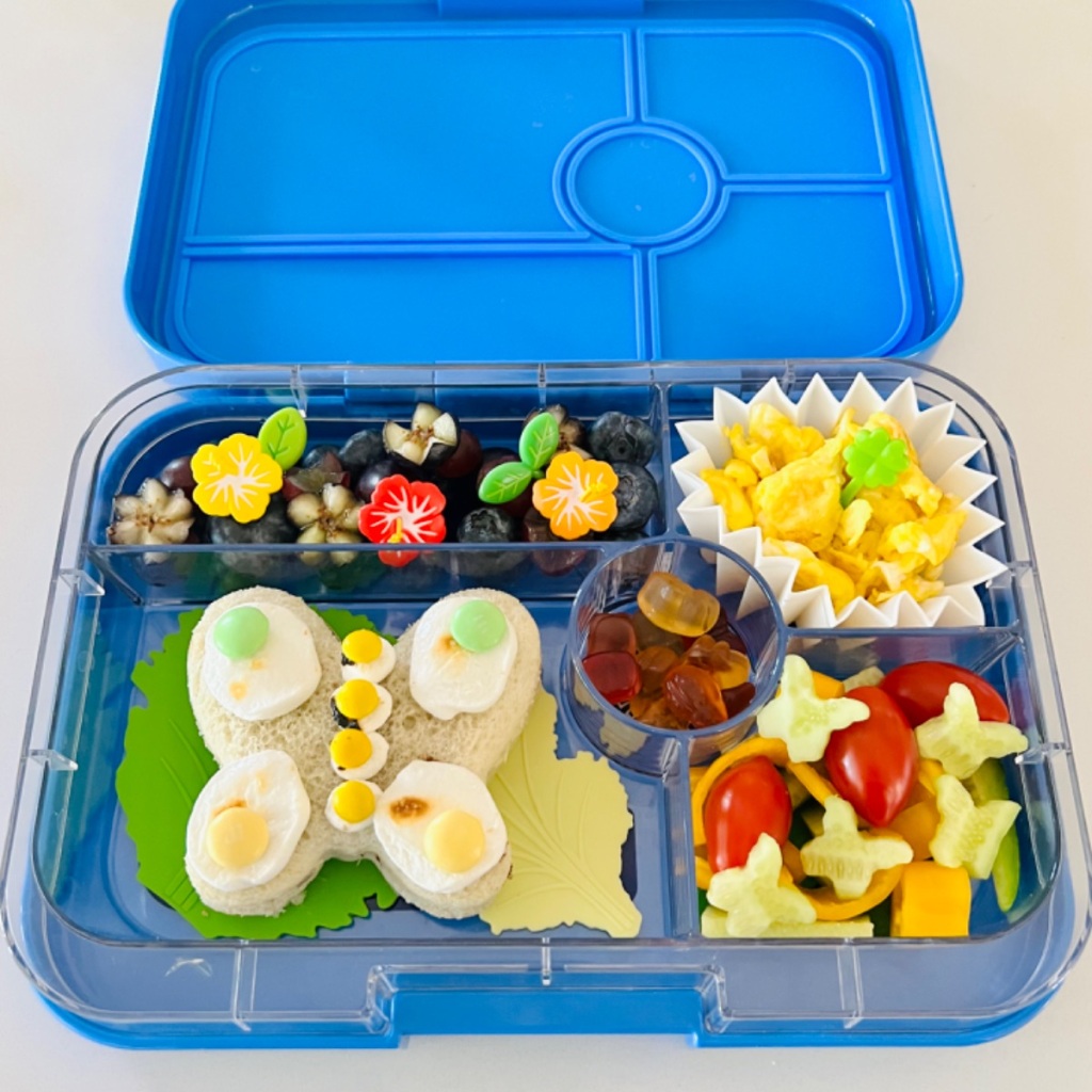 Butterfly-shaped sandwich and colorful veggies on the side in a kid's school lunch in a yumbox bento.